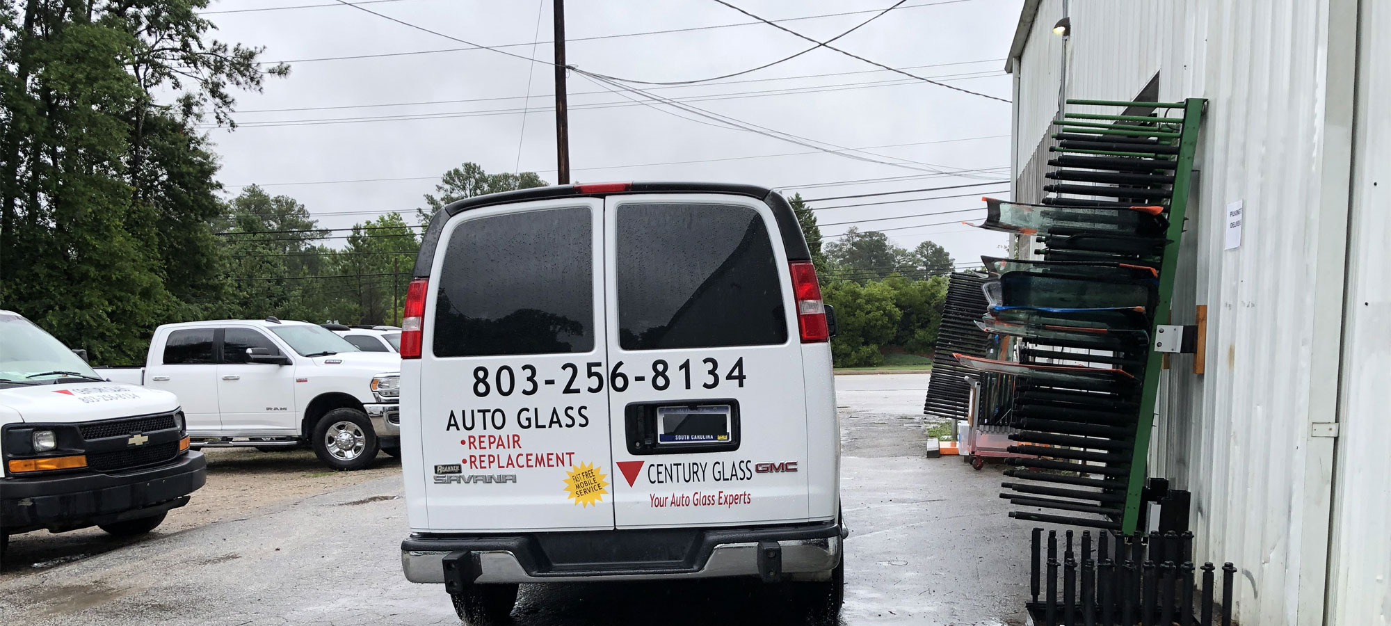 The back of a Century Glass van next to Windshields on a rack.